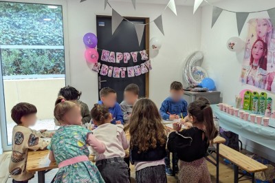 Décoration lumineuse avec le chiffre 18 éclairé et des ballons dorés et blancs dans une pièce sombre.