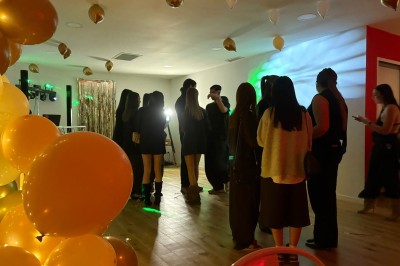 Décoration lumineuse avec le chiffre 18 éclairé et des ballons dorés et blancs dans une pièce sombre.