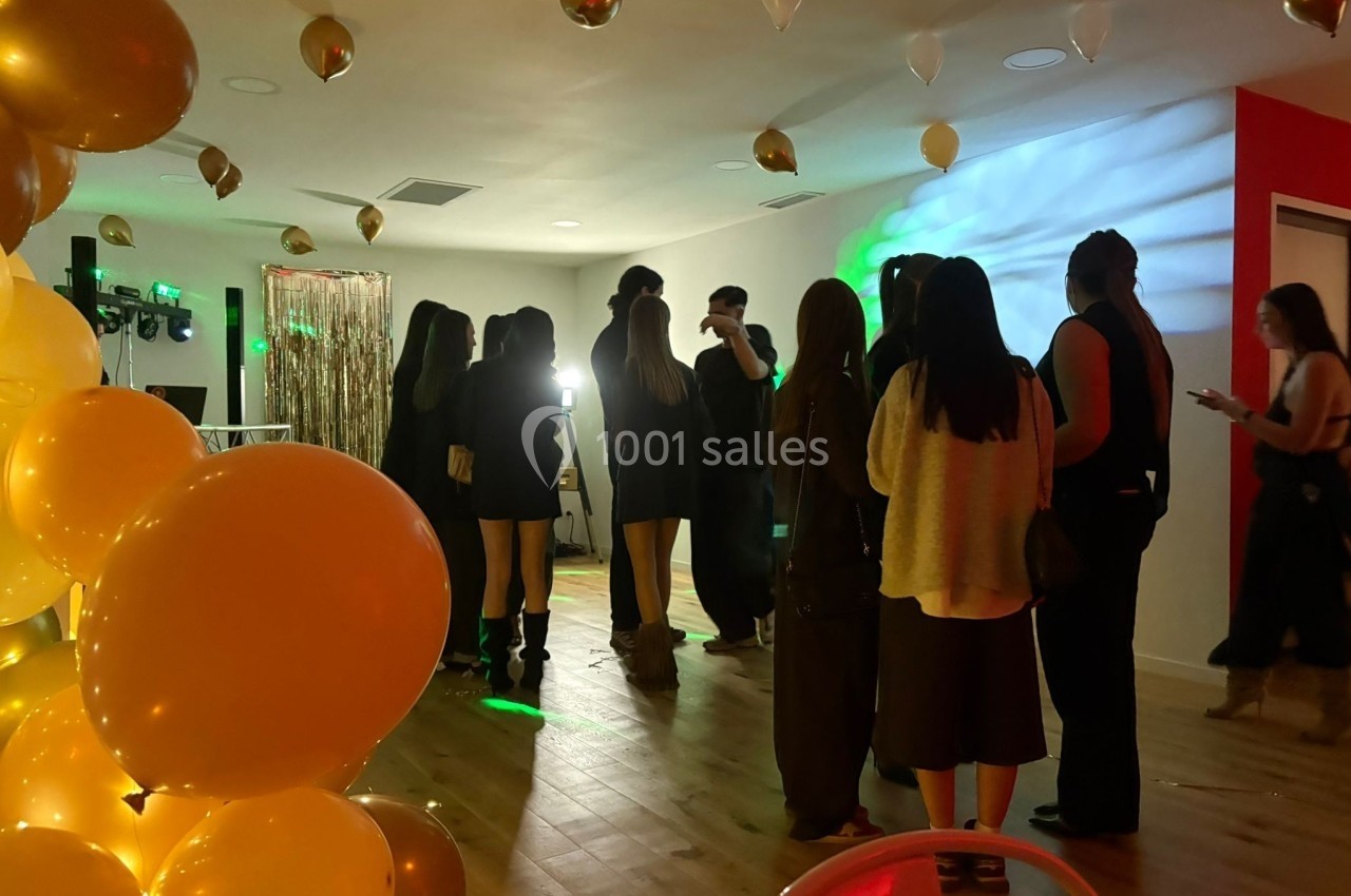 Groupe de personnes discutant dans une salle décorée de ballons dorés et éclairée par des lumières tamisées.