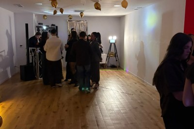 Décoration lumineuse avec le chiffre 18 éclairé et des ballons dorés et blancs dans une pièce sombre.