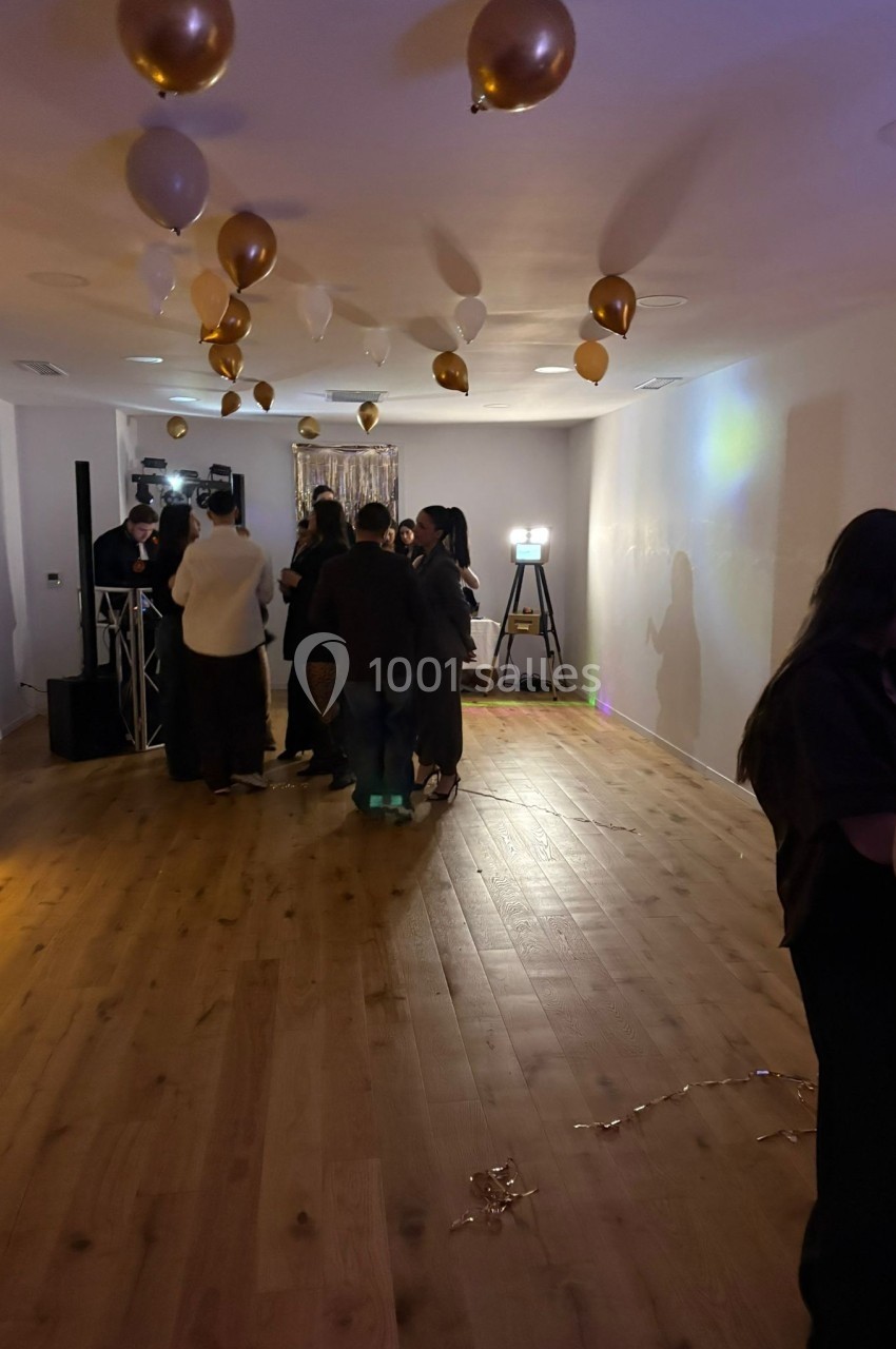 Groupe de personnes discutant dans une salle décorée de ballons dorés et blancs, éclairée par des lumières tamisées.