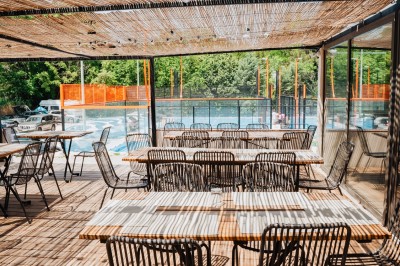 Miniature Location salle Simiane-Collongue (Bouches-du-Rhône) - Restaurant du Cercle #2 Terrain de padel extérieur avec sol bleu, clôtures en verre et grillage, entouré d'arbres et de filets orange.