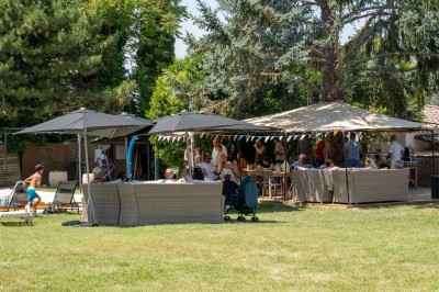Miniature Location salle Simiane-Collongue (Bouches-du-Rhône) - Restaurant du Cercle #5 Terrain de padel extérieur avec sol bleu, clôtures en verre et grillage, entouré d'arbres et de filets orange.