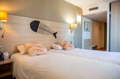 Miniature Chambre Deux lits simples avec tête de lit en bois décorée d'un motif de poisson, dans une chambre lumineuse et moderne.