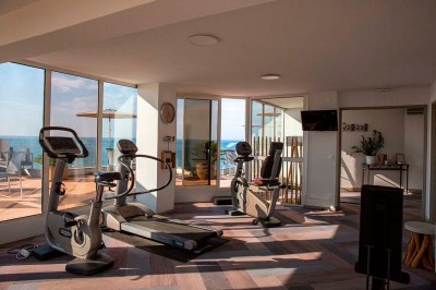 Miniature Salle de sport vue mer Deux lits simples avec tête de lit en bois décorée d'un motif de poisson, dans une chambre lumineuse et moderne.