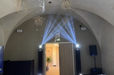 Salle voûtée avec éclairage lumineux, tables dressées et décorations modernes suspendues au plafond.