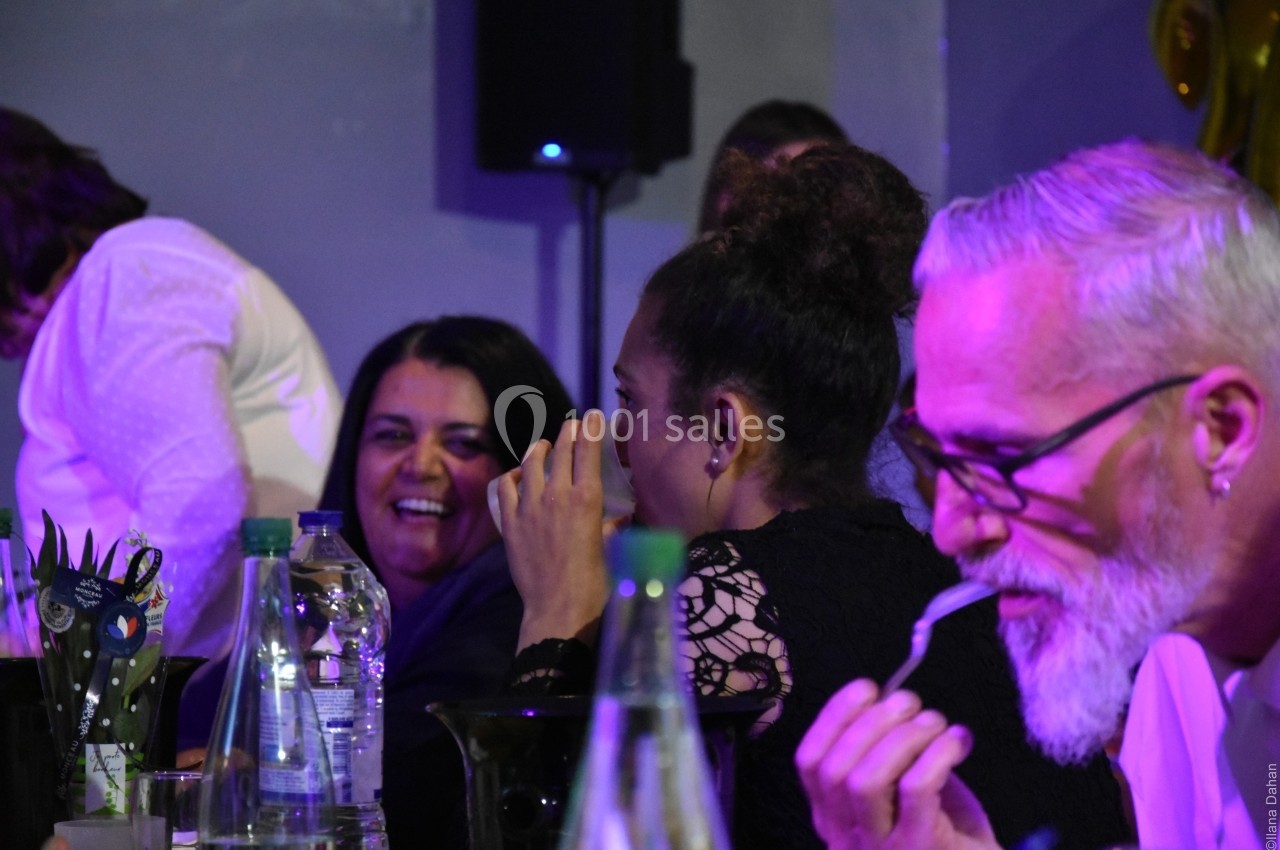 Des personnes assises à une table, discutant et partageant un moment convivial dans un environnement éclairé.