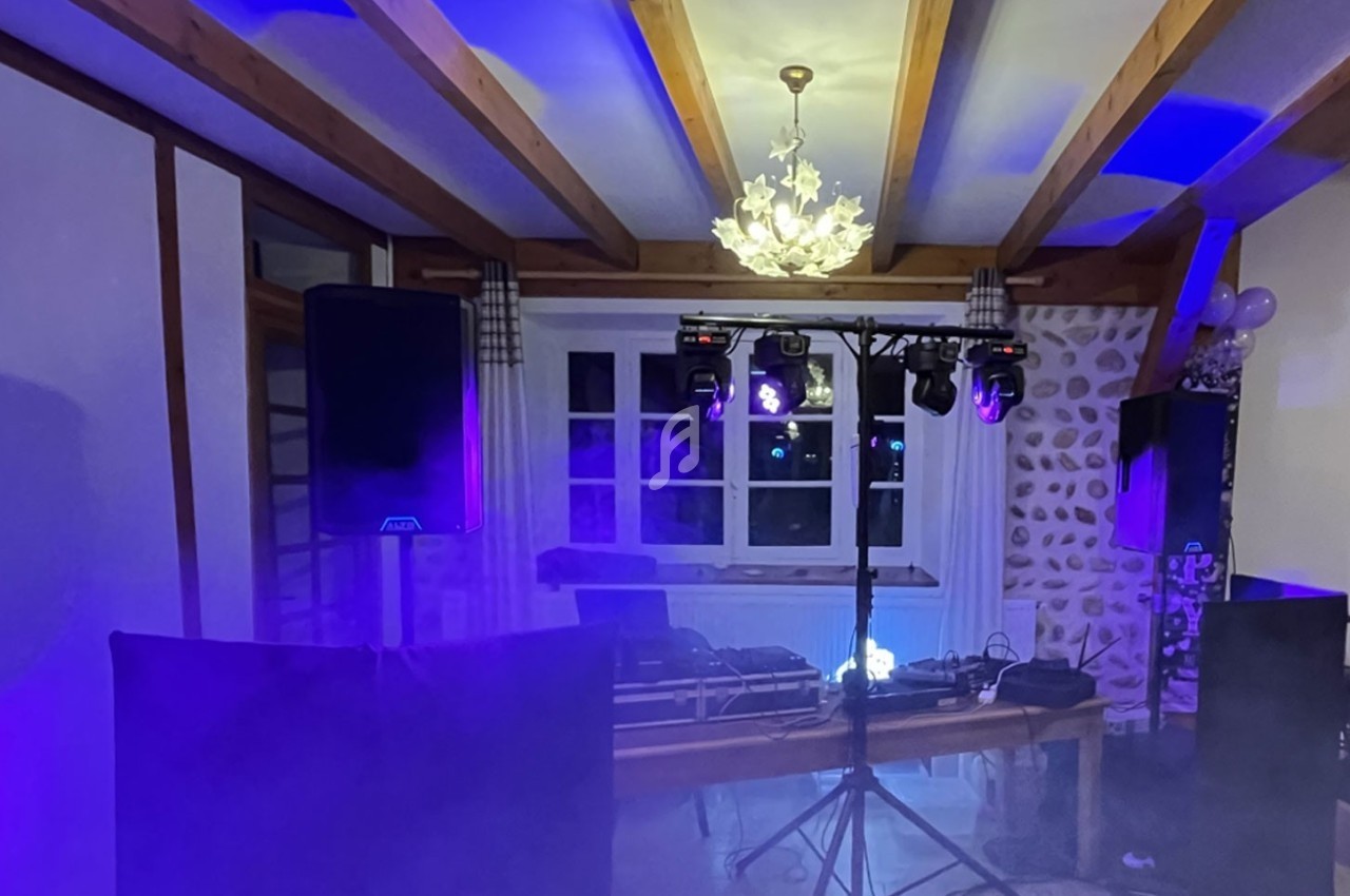 Installation de matériel de sonorisation et éclairage dans une pièce avec plafond en poutres apparentes.