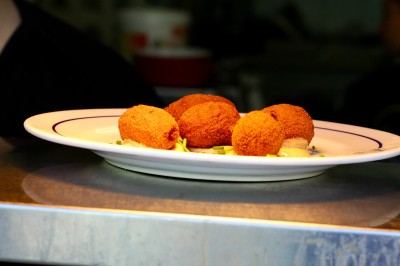 Vue aérienne d'un lac entouré de collines boisées sous un ciel dégagé au coucher du soleil.