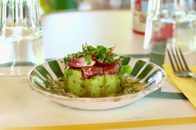Vue aérienne d'un lac entouré de collines boisées sous un ciel dégagé au coucher du soleil.