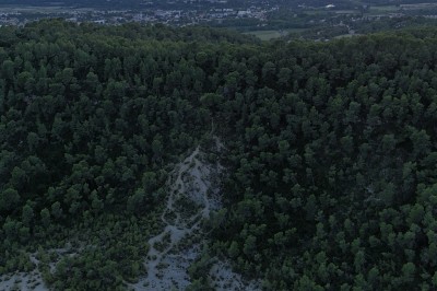 Vue aérienne d'un lac entouré de collines boisées sous un ciel dégagé au coucher du soleil.