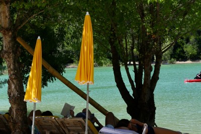 Vue aérienne d'un lac entouré de collines boisées sous un ciel dégagé au coucher du soleil.