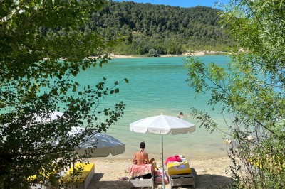 Vue aérienne d'un lac entouré de collines boisées sous un ciel dégagé au coucher du soleil.