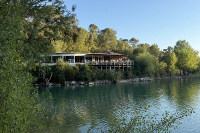 Vue aérienne d'un lac entouré de collines boisées sous un ciel dégagé au coucher du soleil.