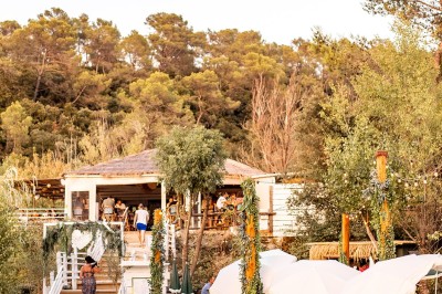Vue aérienne d'un lac entouré de collines boisées sous un ciel dégagé au coucher du soleil.