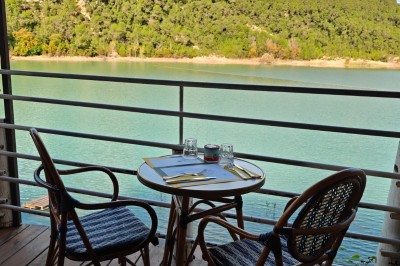 Vue aérienne d'un lac entouré de collines boisées sous un ciel dégagé au coucher du soleil.