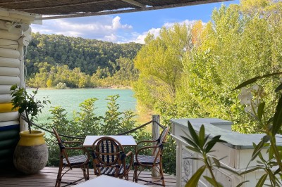 Vue aérienne d'un lac entouré de collines boisées sous un ciel dégagé au coucher du soleil.