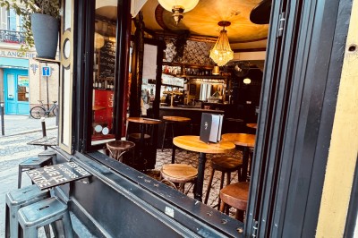 Bouteille de champagne dans un seau en métal, entourée de verres et d'un bouquet de fleurs, devant une tireuse à bière dorée.