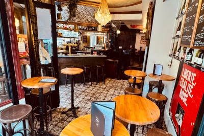 Bouteille de champagne dans un seau en métal, entourée de verres et d'un bouquet de fleurs, devant une tireuse à bière dorée.