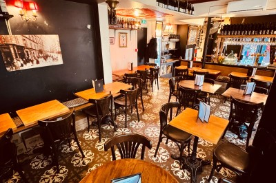 Bouteille de champagne dans un seau en métal, entourée de verres et d'un bouquet de fleurs, devant une tireuse à bière dorée.