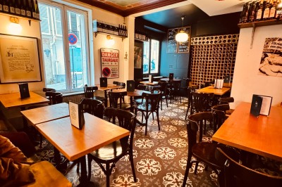 Bouteille de champagne dans un seau en métal, entourée de verres et d'un bouquet de fleurs, devant une tireuse à bière dorée.