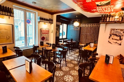 Bouteille de champagne dans un seau en métal, entourée de verres et d'un bouquet de fleurs, devant une tireuse à bière dorée.