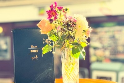 Bouteille de champagne dans un seau en métal, entourée de verres et d'un bouquet de fleurs, devant une tireuse à bière dorée.