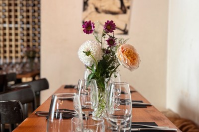 Bouteille de champagne dans un seau en métal, entourée de verres et d'un bouquet de fleurs, devant une tireuse à bière dorée.