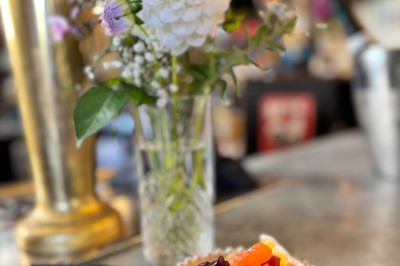 Bouteille de champagne dans un seau en métal, entourée de verres et d'un bouquet de fleurs, devant une tireuse à bière dorée.