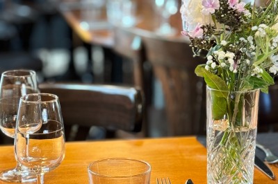Bouteille de champagne dans un seau en métal, entourée de verres et d'un bouquet de fleurs, devant une tireuse à bière dorée.