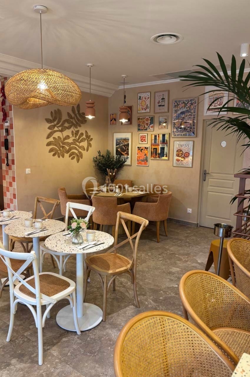 Salle de restaurant lumineuse avec tables en marbre, chaises en rotin, décoration murale et plantes.