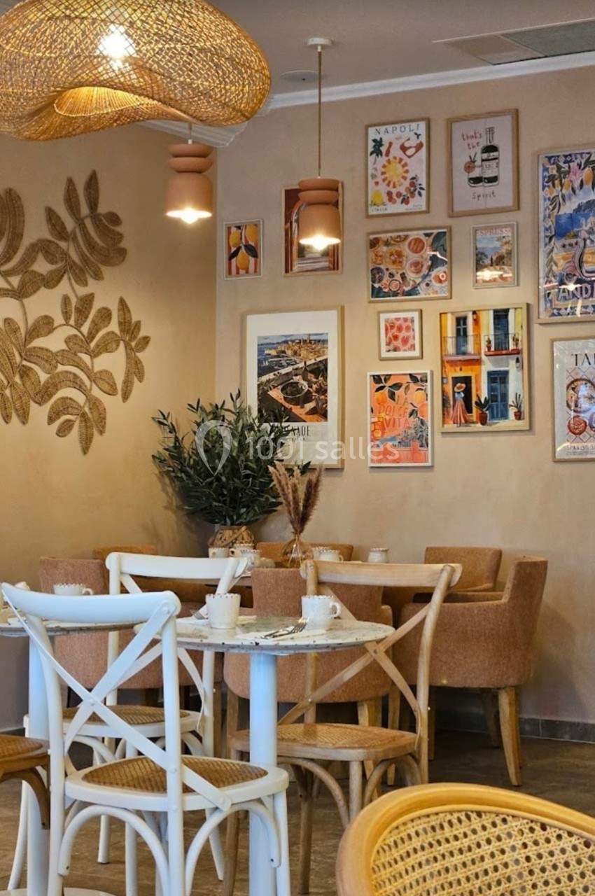 Salle de restaurant décorée avec des affiches colorées, des meubles en bois clair et des luminaires en osier.