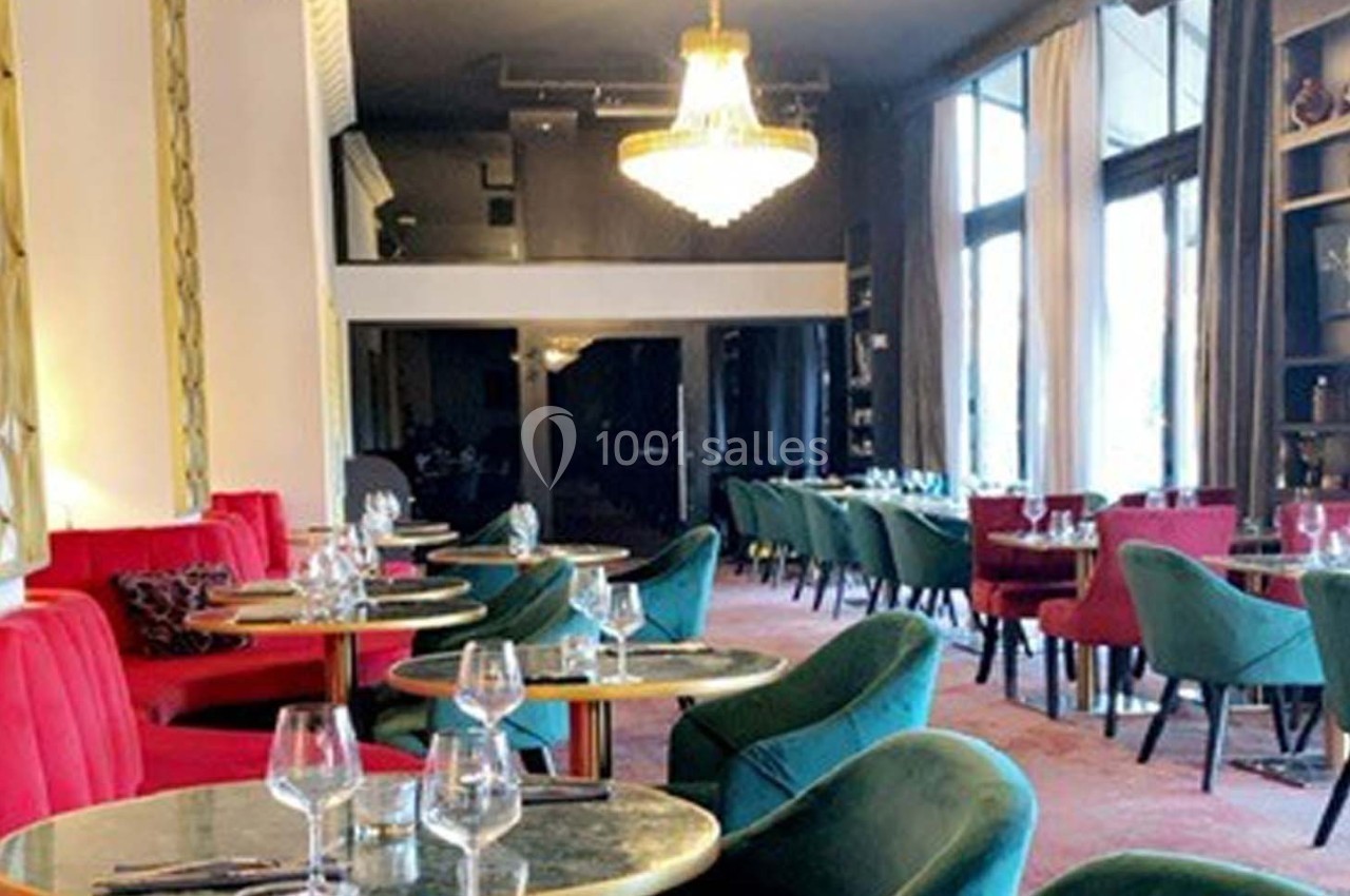 Salle de restaurant élégante avec tables en marbre, chaises colorées et grand lustre central.