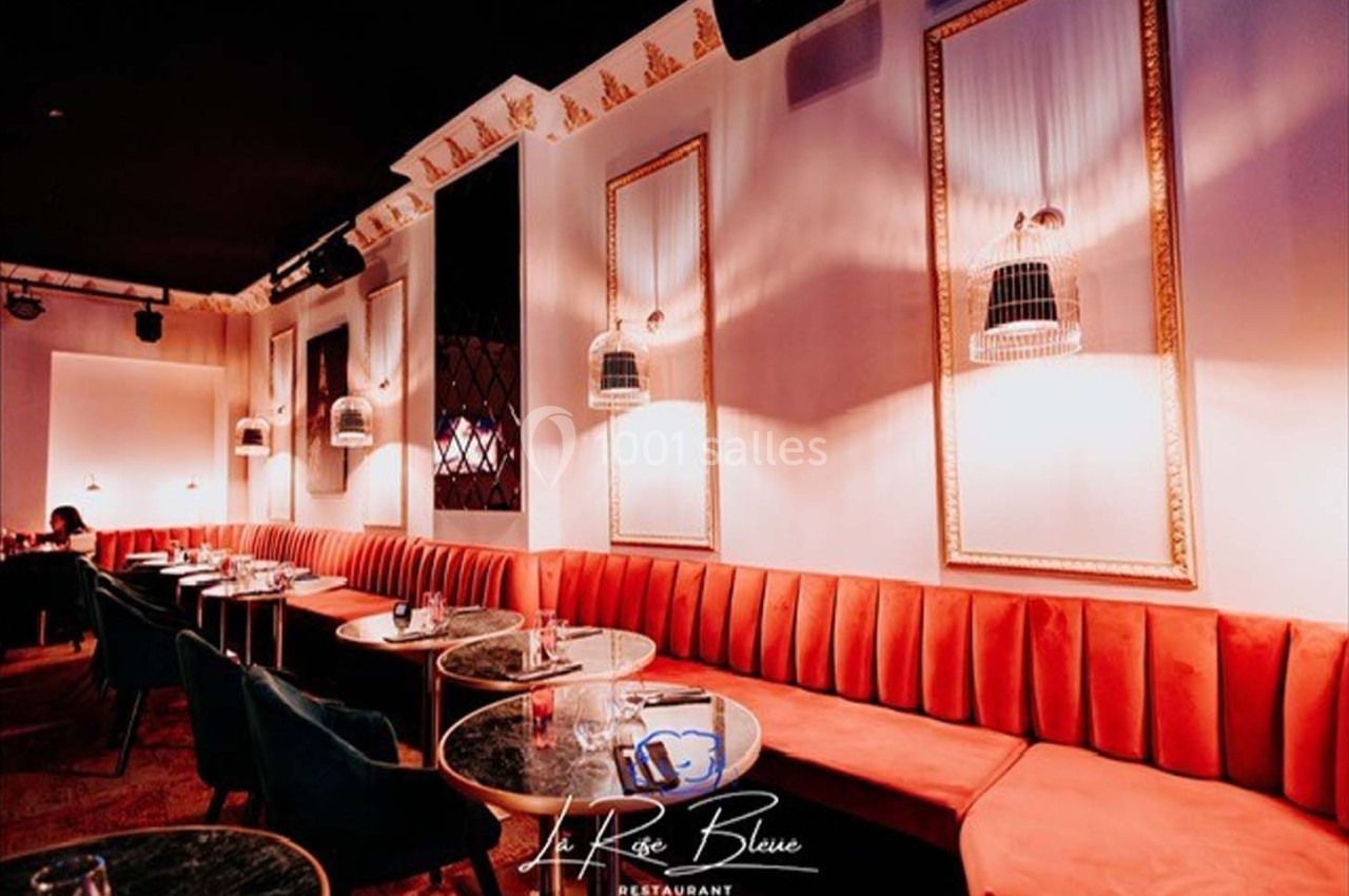 Banquettes rouges et tables rondes dans un restaurant élégant avec éclairage tamisé et décoration raffinée.