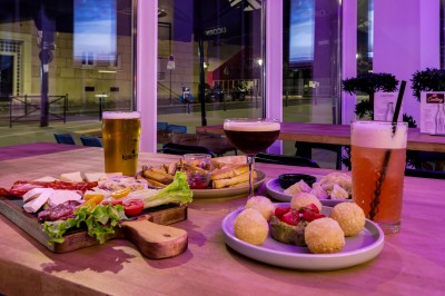 Plateau de charcuterie et fromages, frites, raviolis et boulettes servis sur une table en bois dans un restaurant.