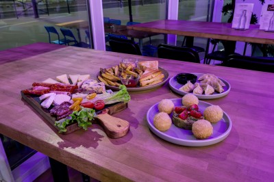 Plateau de charcuterie et fromages, frites, raviolis et boulettes servis sur une table en bois dans un restaurant.