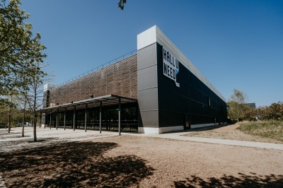 Comptoir en bois avec deux ordinateurs dans une salle d'arcade lumineuse, entourée de jeux et de machines.
