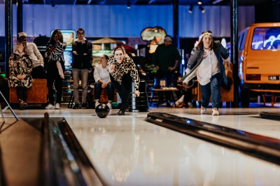 Comptoir en bois avec deux ordinateurs dans une salle d'arcade lumineuse, entourée de jeux et de machines.