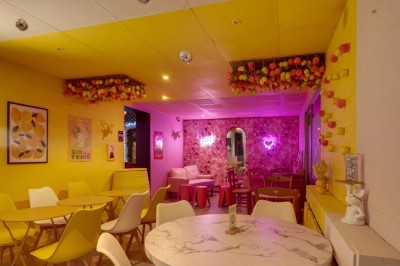 Miniature Location salle Mérignac (Gironde) - Hope Bar #8 Salle de bar avec éclairage coloré, tables hautes, chaises noires et décorations lumineuses au mur.