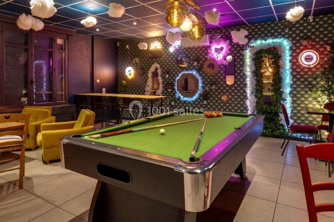 Salle de loisirs avec une table de billard, des fauteuils colorés et une décoration lumineuse et originale.
