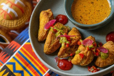 Cercle orné de motifs colorés entourant le mot ’OKRA’ sur un fond bleu foncé.