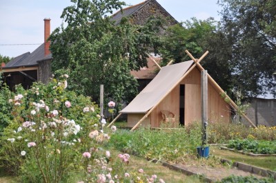 Miniature Location salle Broualan (Ille-et-Vilaine) - La Ferme du Domaine #20 Des poneys et une vache se reposent et broutent dans un pré clôturé, avec une cabane en bois en arrière-plan.