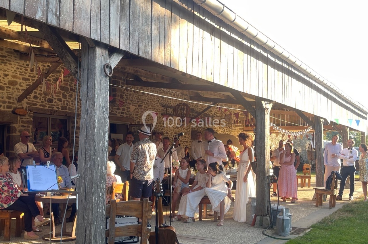 Groupe de personnes rassemblées sous un auvent en bois lors d'un événement convivial en extérieur par temps ensoleillé.