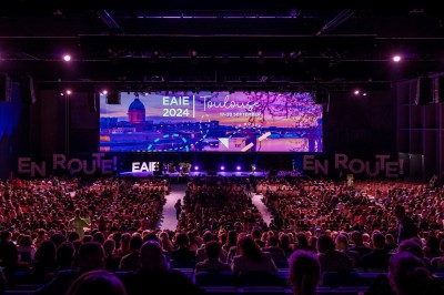 Miniature Destination Occitanie #3 Un groupe de personnes discute dans un jardin, entouré de plantes et d'arbres sous un ciel bleu.