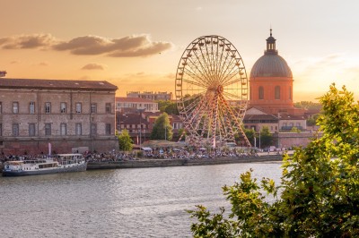 Miniature Destination Occitanie #5 Un groupe de personnes discute dans un jardin, entouré de plantes et d'arbres sous un ciel bleu.