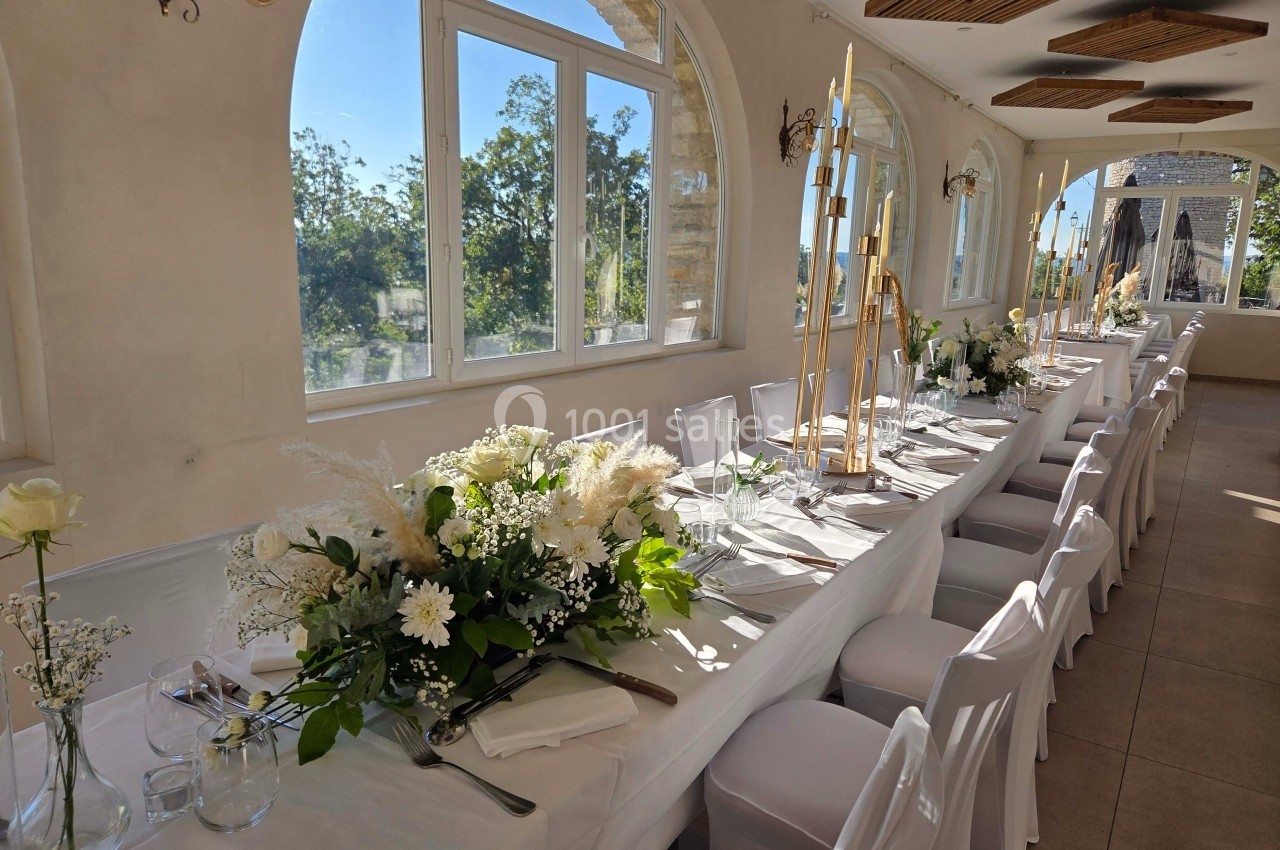 Table de réception élégamment dressée avec nappes blanches, bouquets de fleurs et chandeliers dorés, dans une salle…