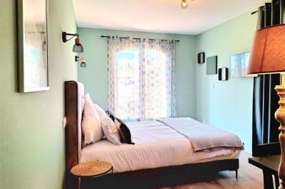 Miniature Location salle Sainte-Tulle (Alpes-de-Haute-Provence) - Domaine de la Mautanne #33 Chambre lumineuse avec lit double, murs verts, rideaux à motifs, lampe de chevet et décoration murale moderne.