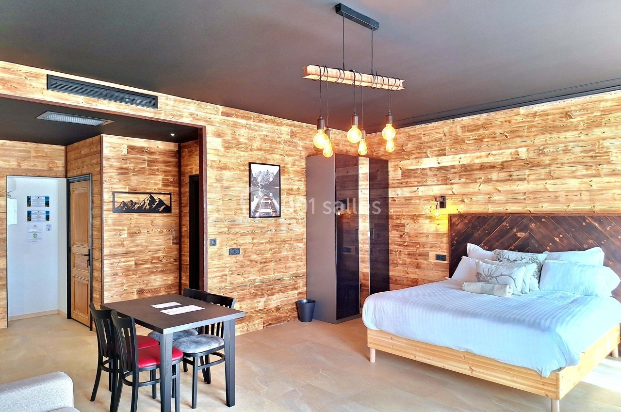 Chambre moderne en bois avec lit double, table à manger, luminaires suspendus et décoration chaleureuse.