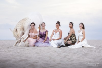 Miniature Lpc Event #4 Deux femmes en costumes ornés posent à côté d'un cheval blanc dans un jardin ensoleillé.