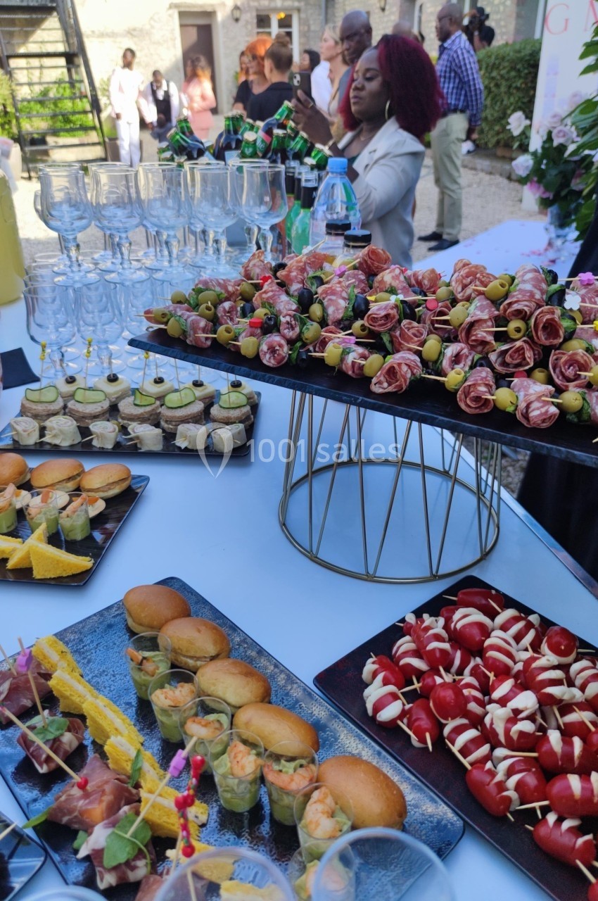Buffet de réception avec verrines, brochettes, mini-sandwichs et amuse-bouches disposés sur une table.